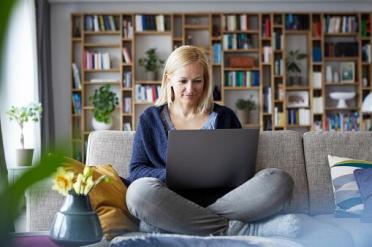 Woman sitting on sofa with a laptop